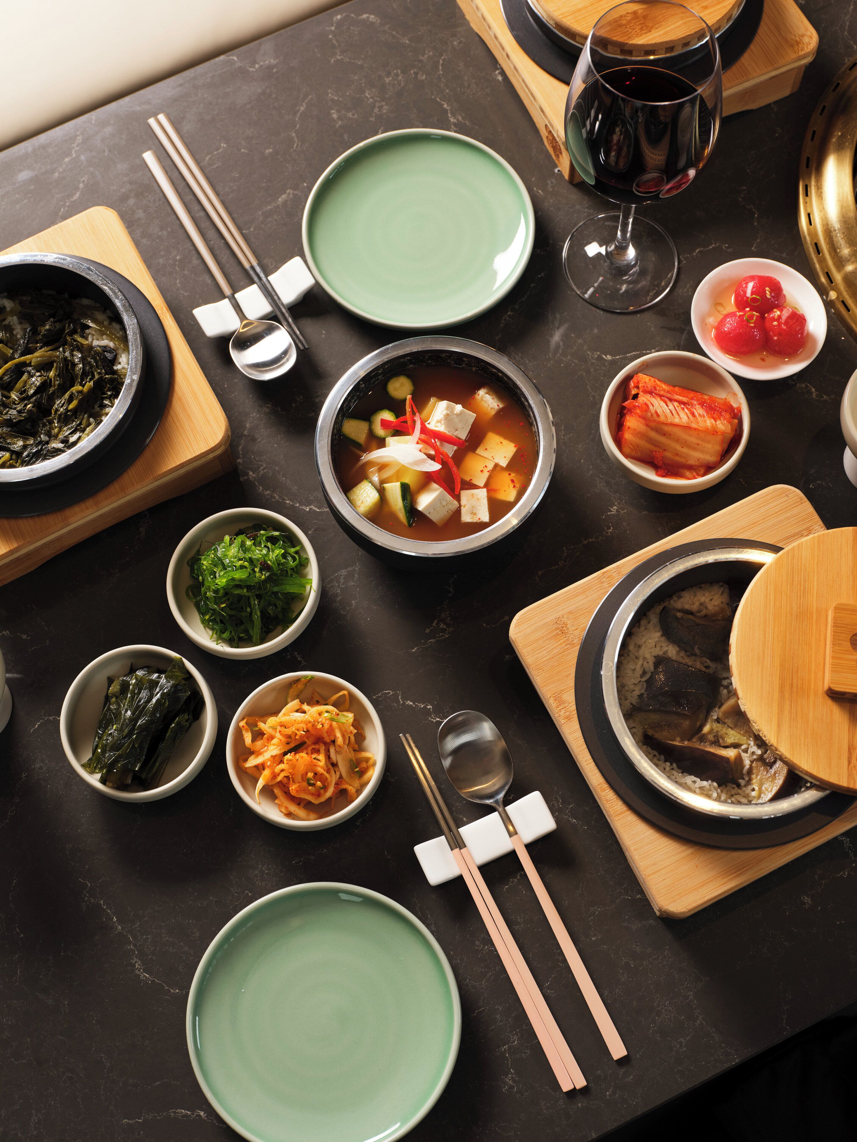A table set with various dishes, including a bowl of soup, a plate of kimchi, and a bowl of rice.