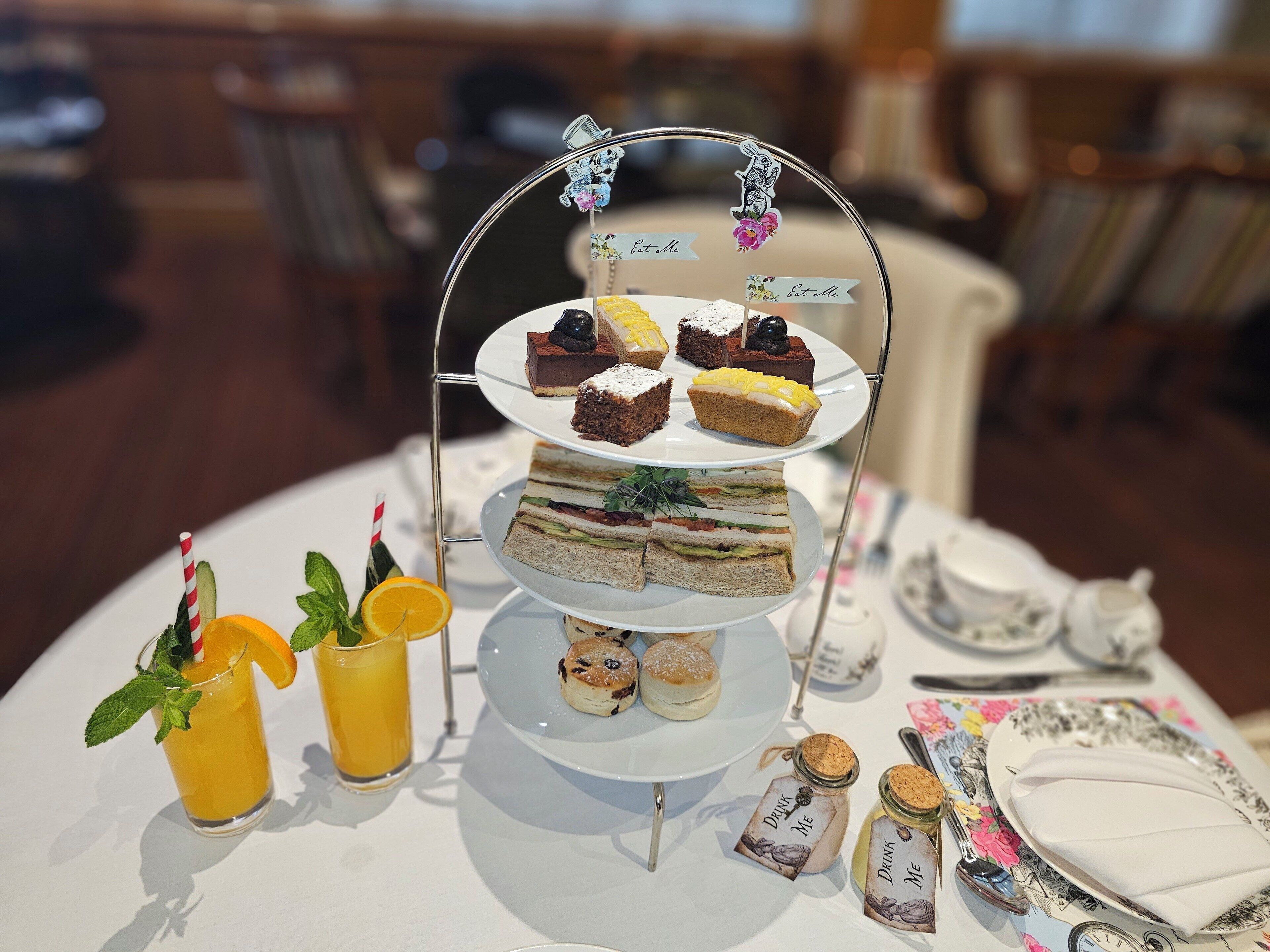 A tiered dessert stand with various pastries and a drink with a straw.