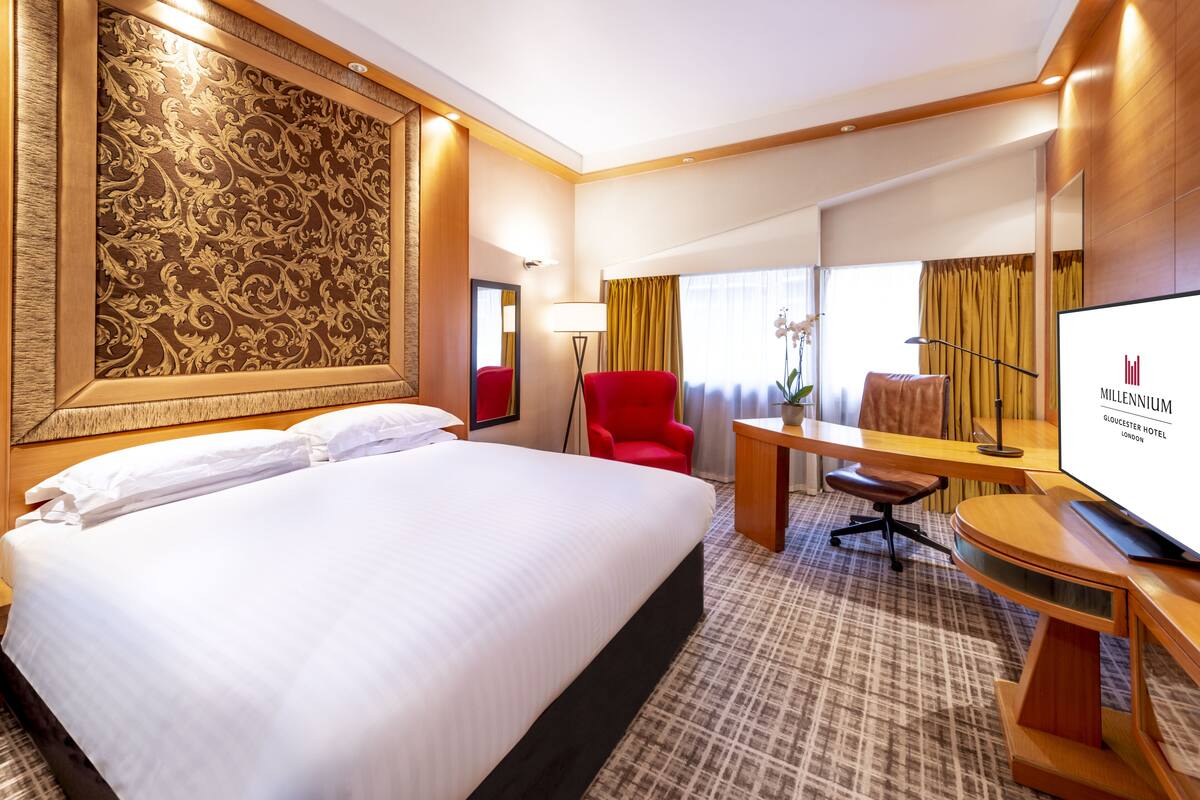 Una habitación de hotel con una cama grande, un escritorio con silla, televisión y espejo.