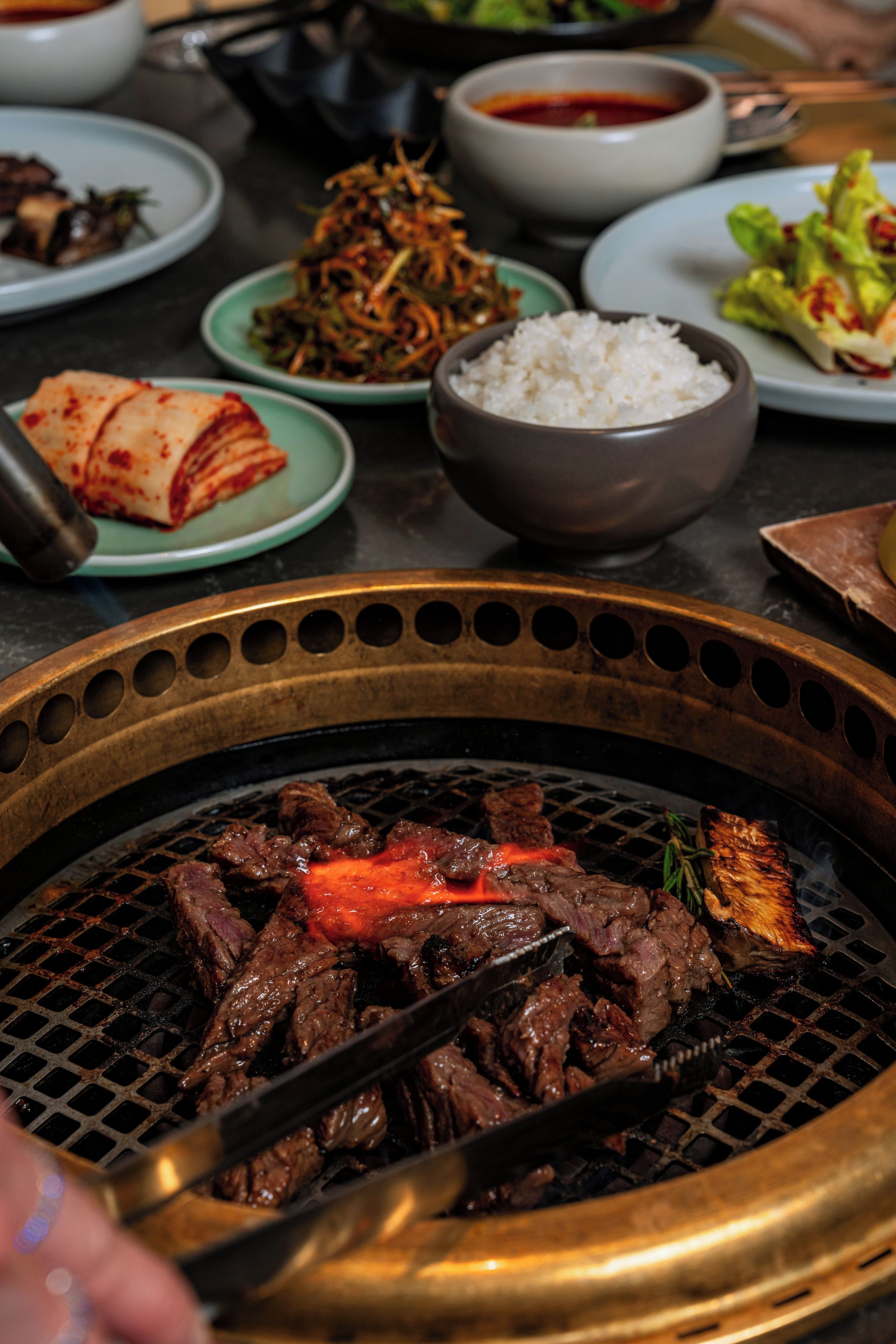 A variety of dishes including grilled meat, rice, and vegetables on a table.