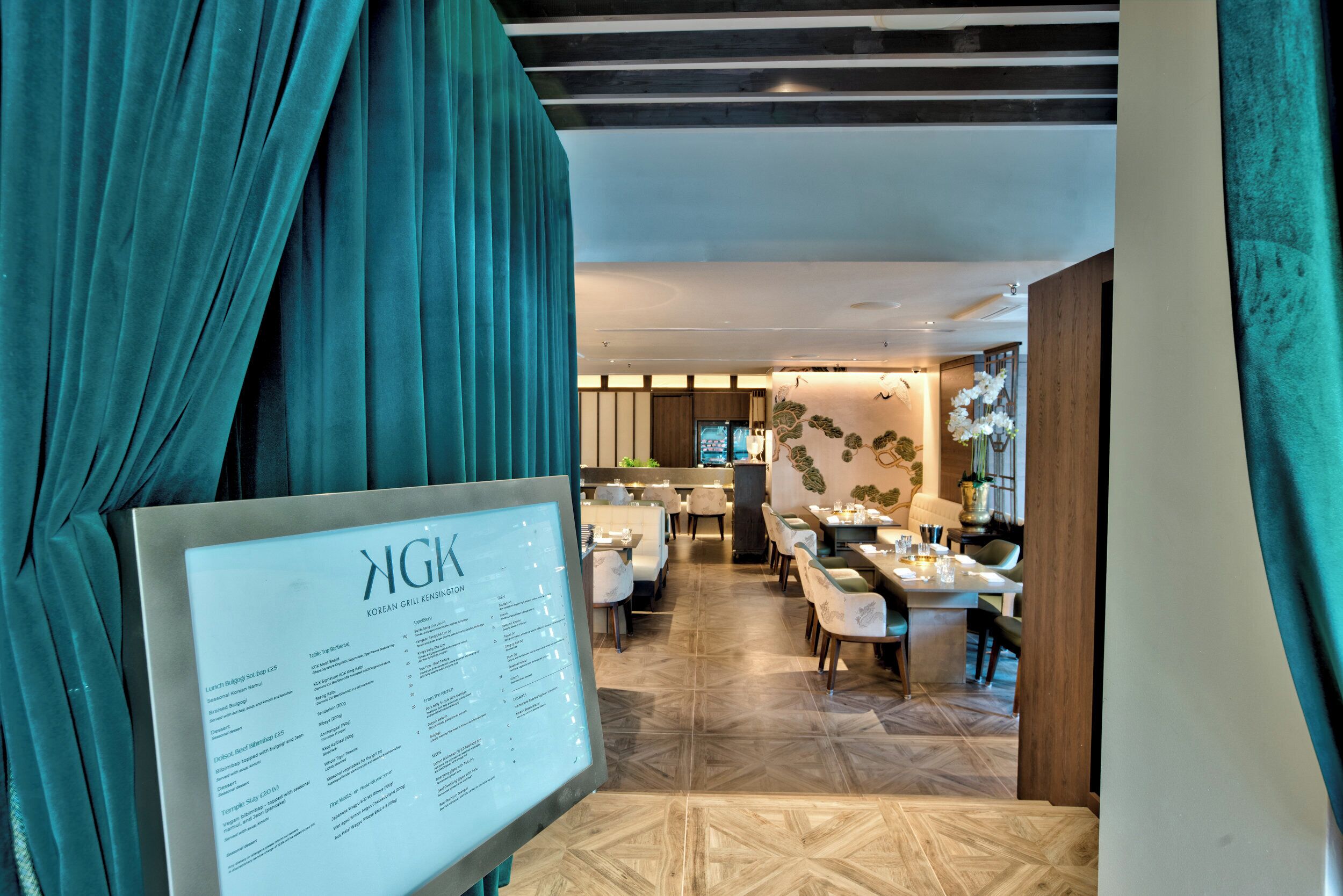 A restaurant with a menu board, wooden flooring, and a view of the dining area.