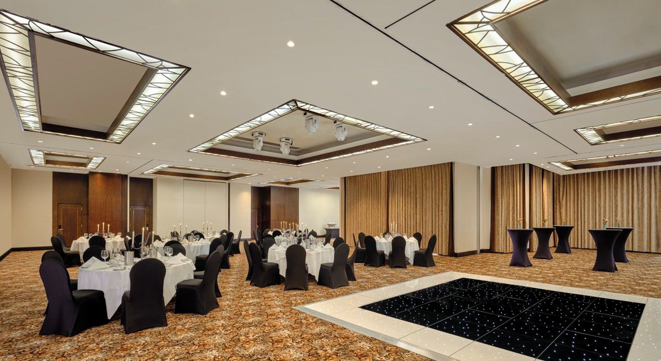 A conference room with round tables, black chairs, and a central dance floor.