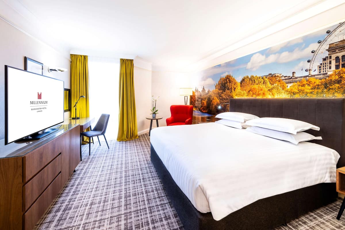 Habitación de hotel con cama, televisión, escritorio y una silla.