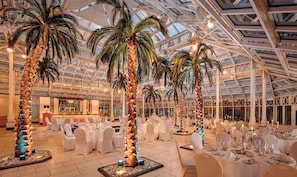 A spacious indoor venue with high ceilings and a glass roof, featuring multiple dining tables set for events. - Millennium Hotel and Conference Centre Gloucester London (London)