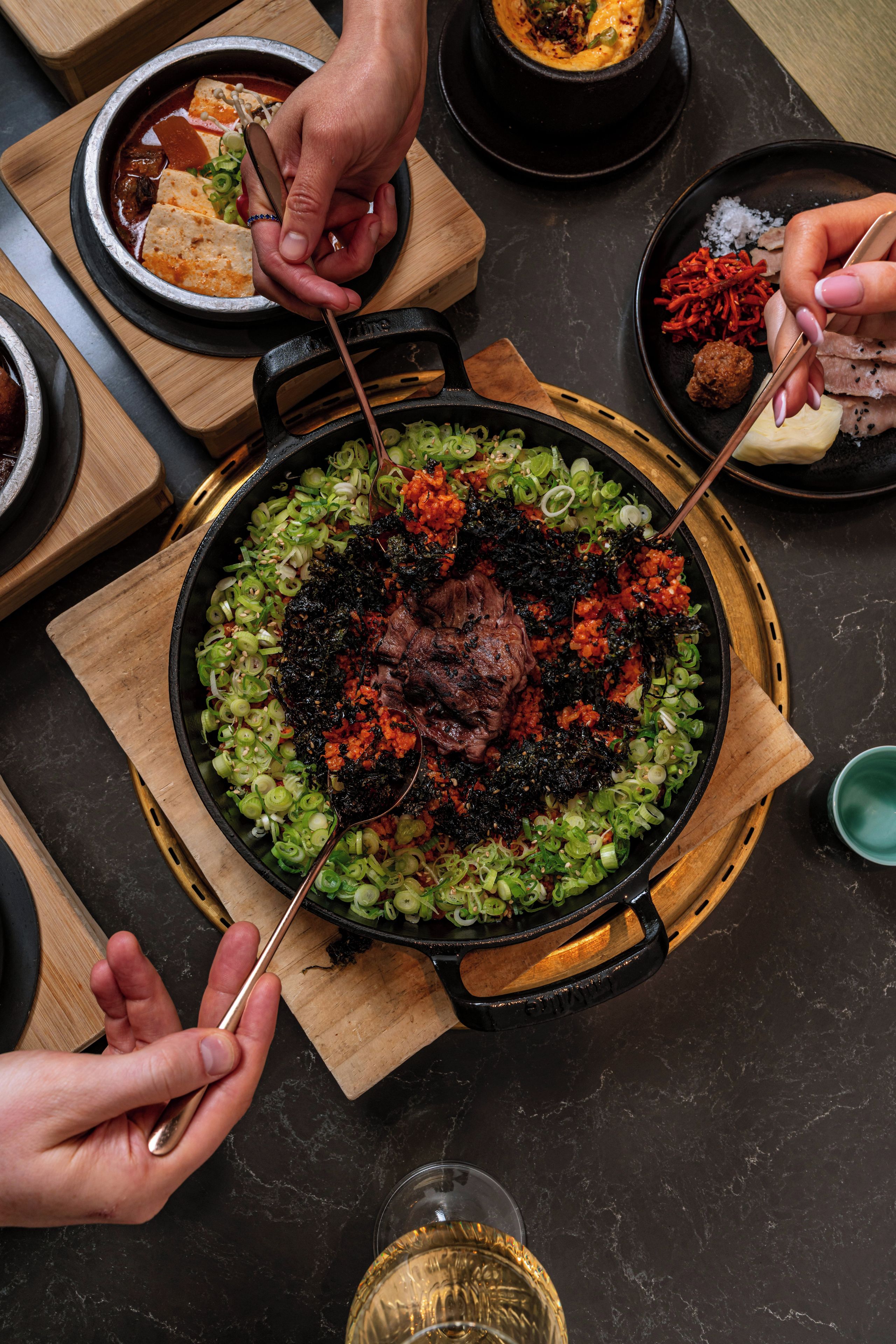 A dining table with a central dish of food, surrounded by various side dishes and utensils.