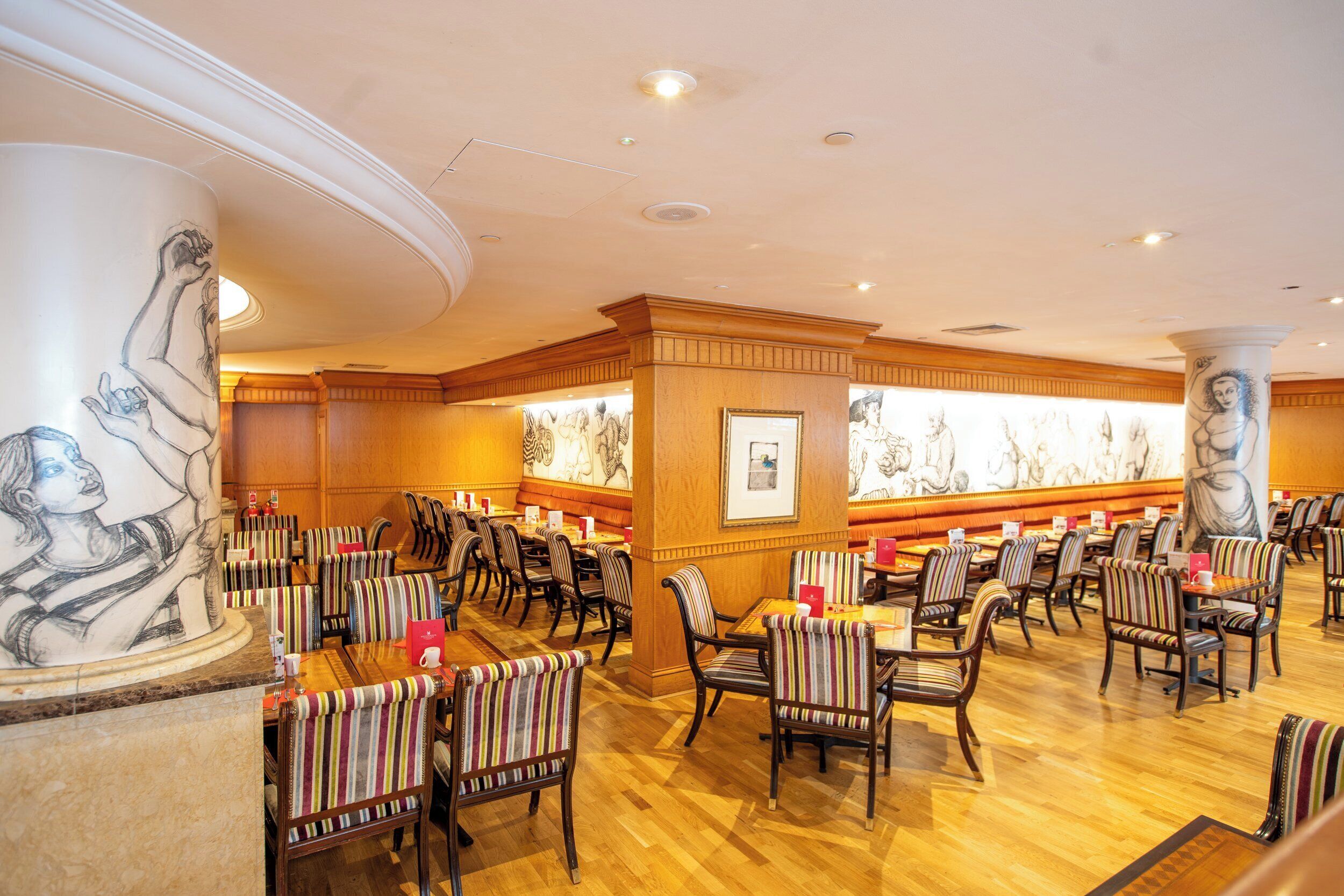 A restaurant with striped chairs, wooden tables, and marble columns.
