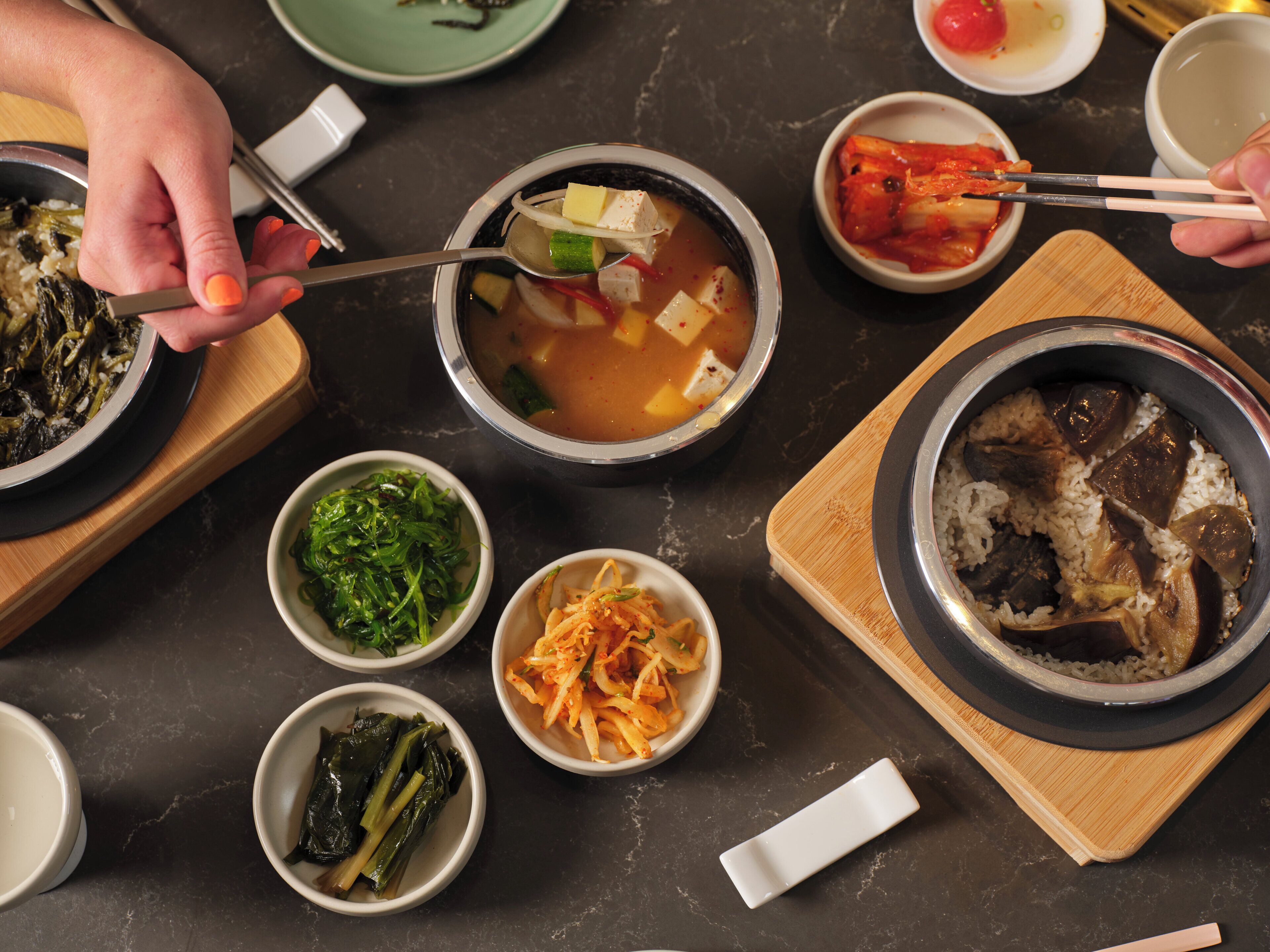 A variety of dishes including a bowl of soup, kimchi, and rice.