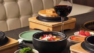 A dining table with various dishes, a glass of red wine, and a cushioned chair in the background.