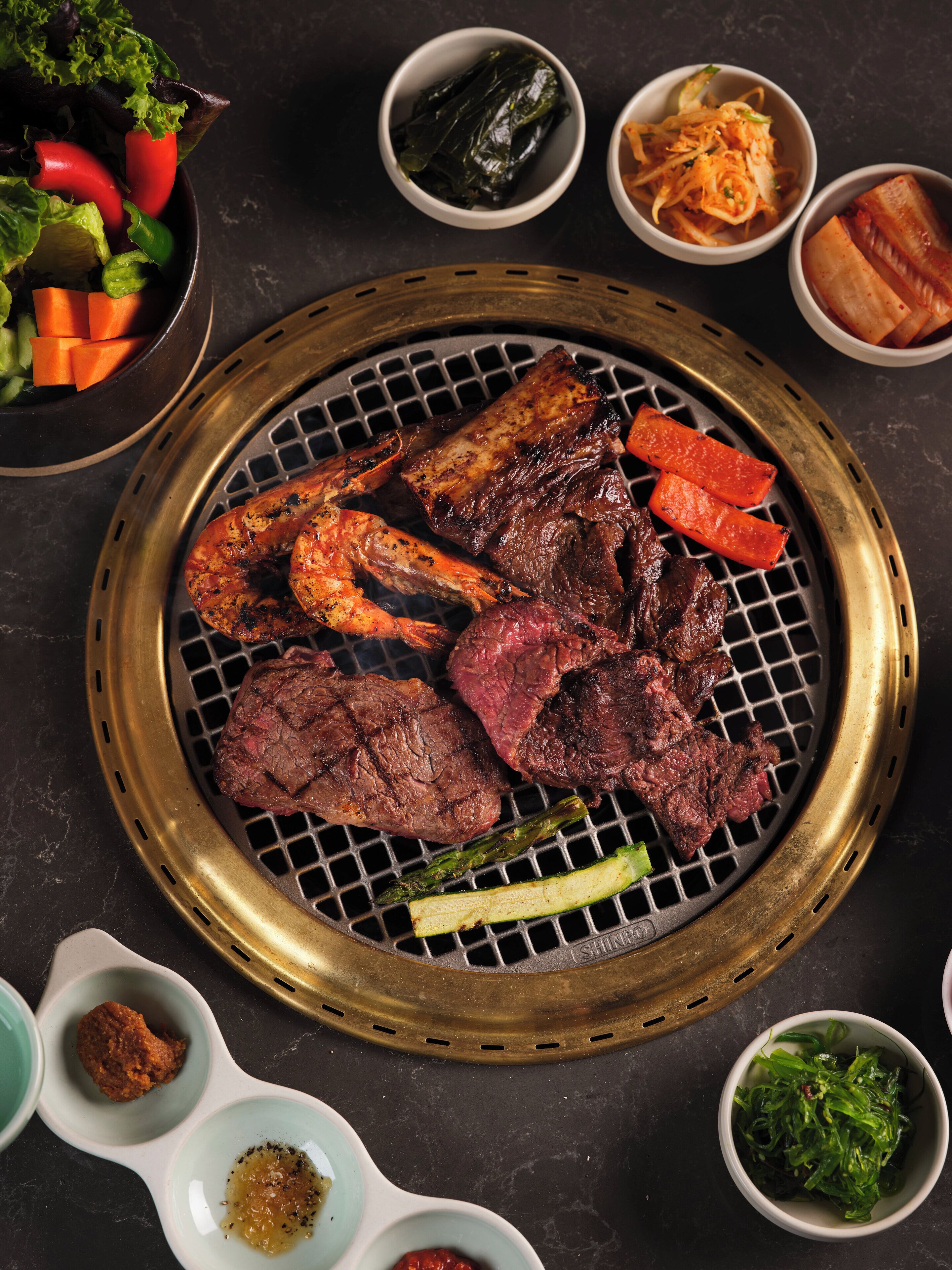 Una parrilla con carnes y verduras variadas.