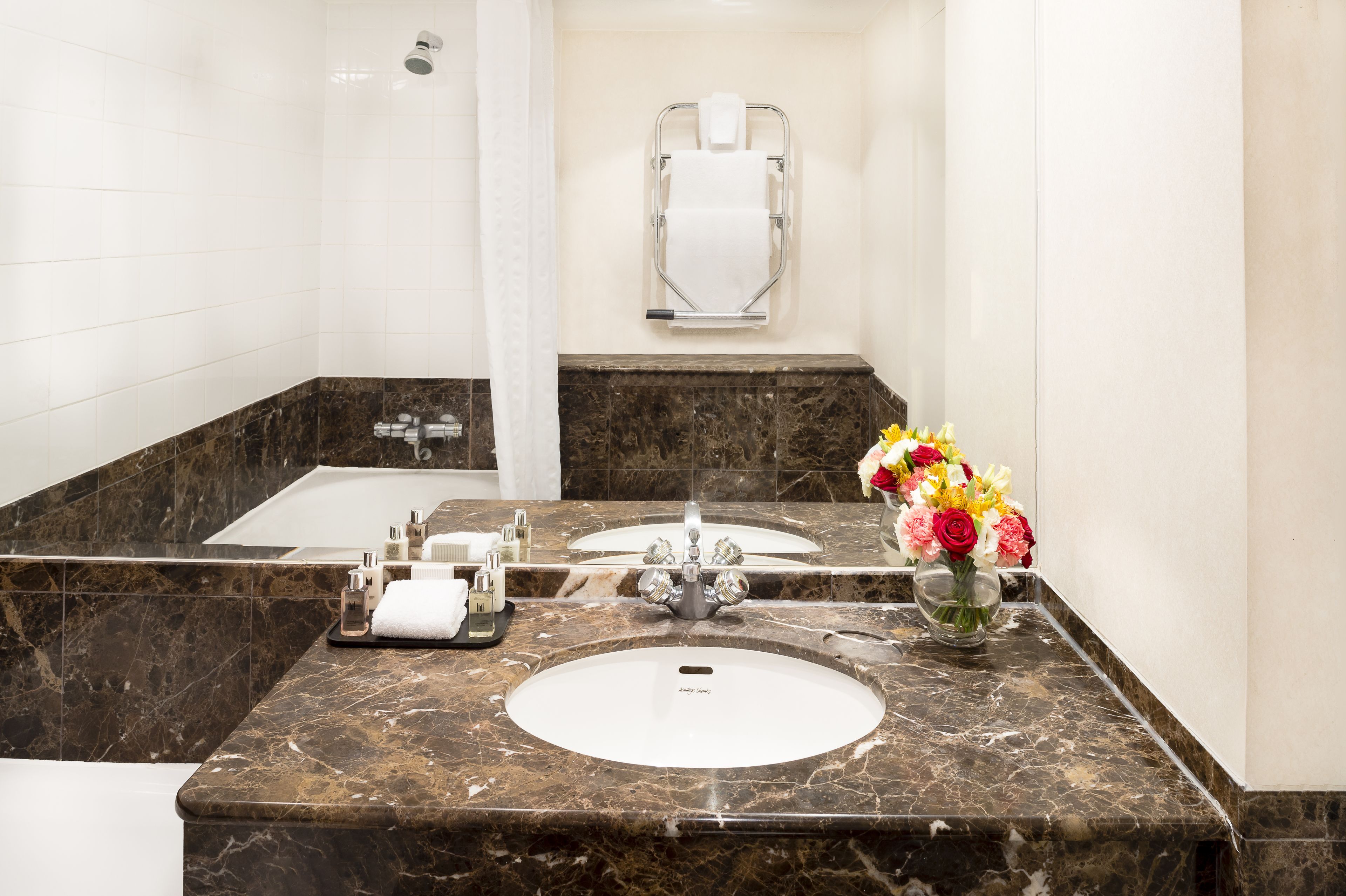 A bathroom with a marble sink, a bathtub, a shower, and a towel rack.