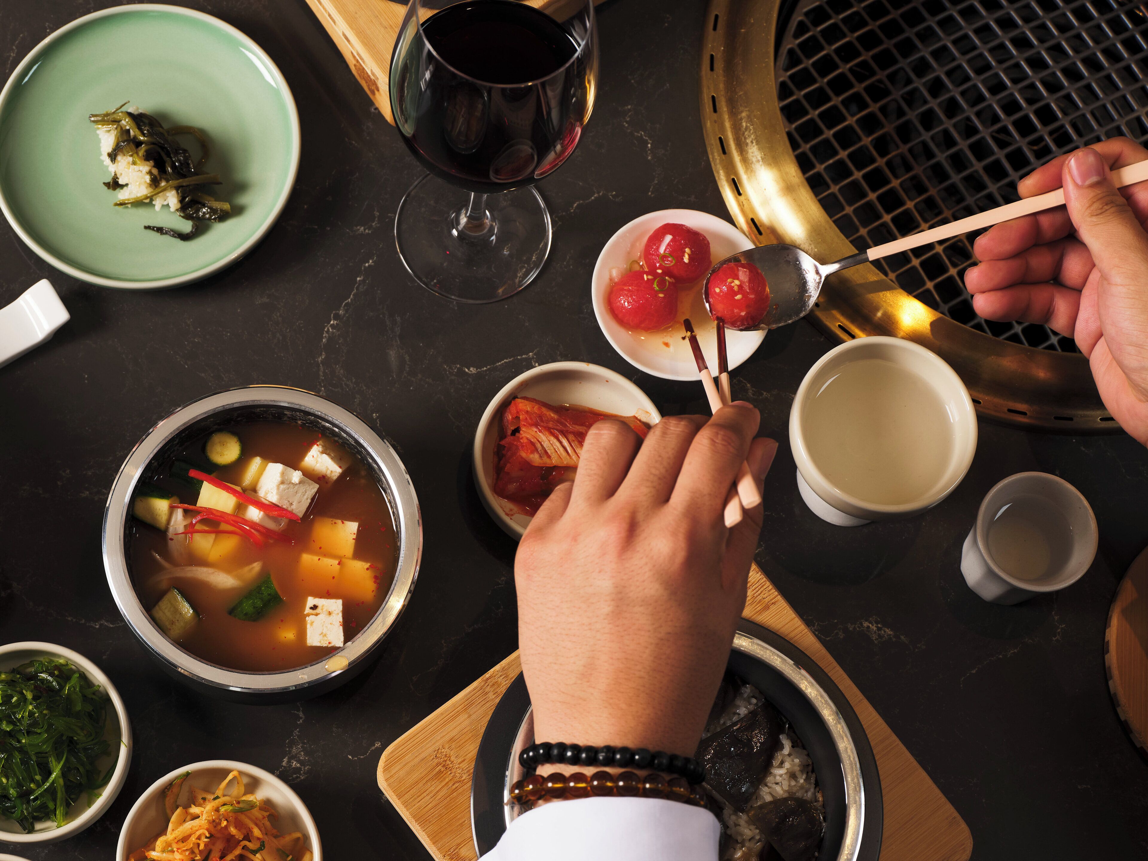 A dining table with various dishes, including a bowl of soup, a plate of rice, and a glass of red wine.