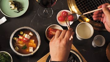 Una mesa de comedor con varios platos, incluyendo un tazón de sopa, una porción de arroz y una copa de vino tinto.