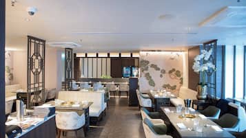 A modern restaurant with a central bar, multiple dining areas, and a decorative wall mural.