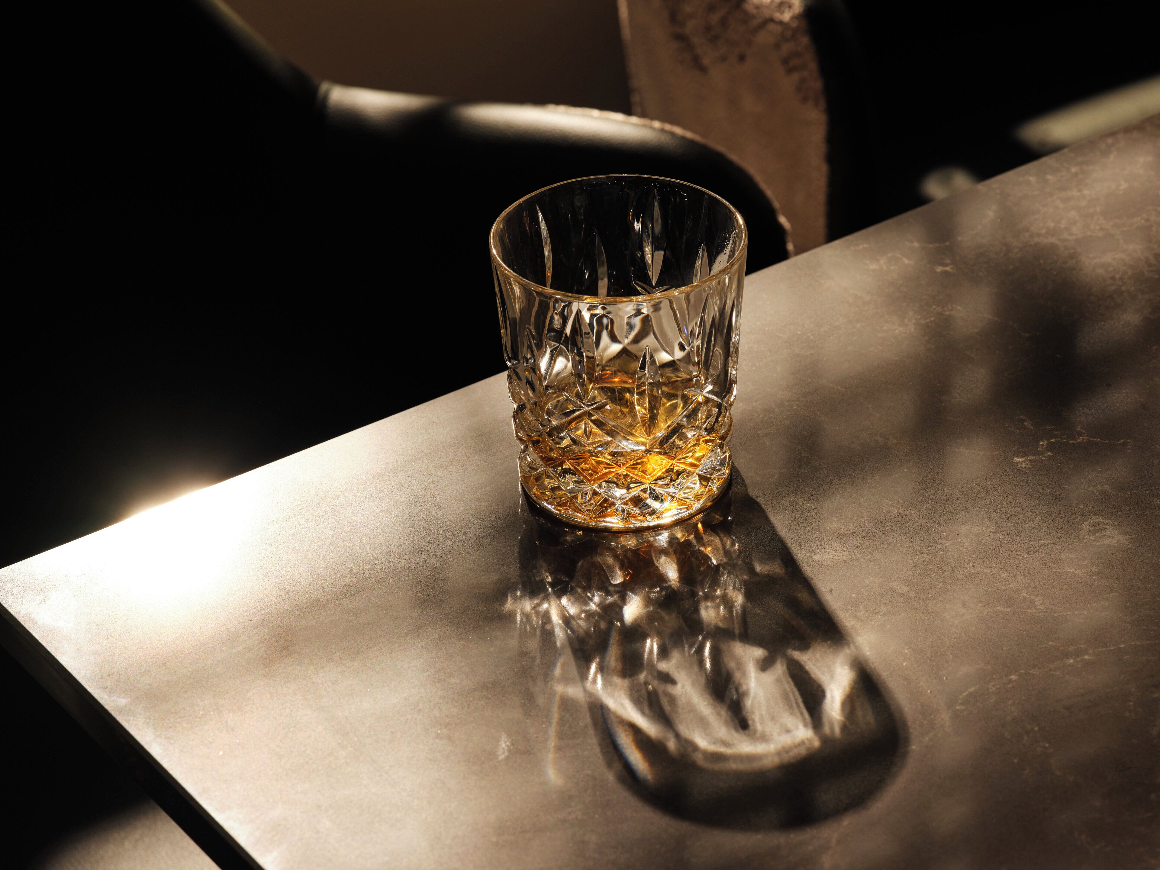 A clear glass with a textured design on a reflective surface.