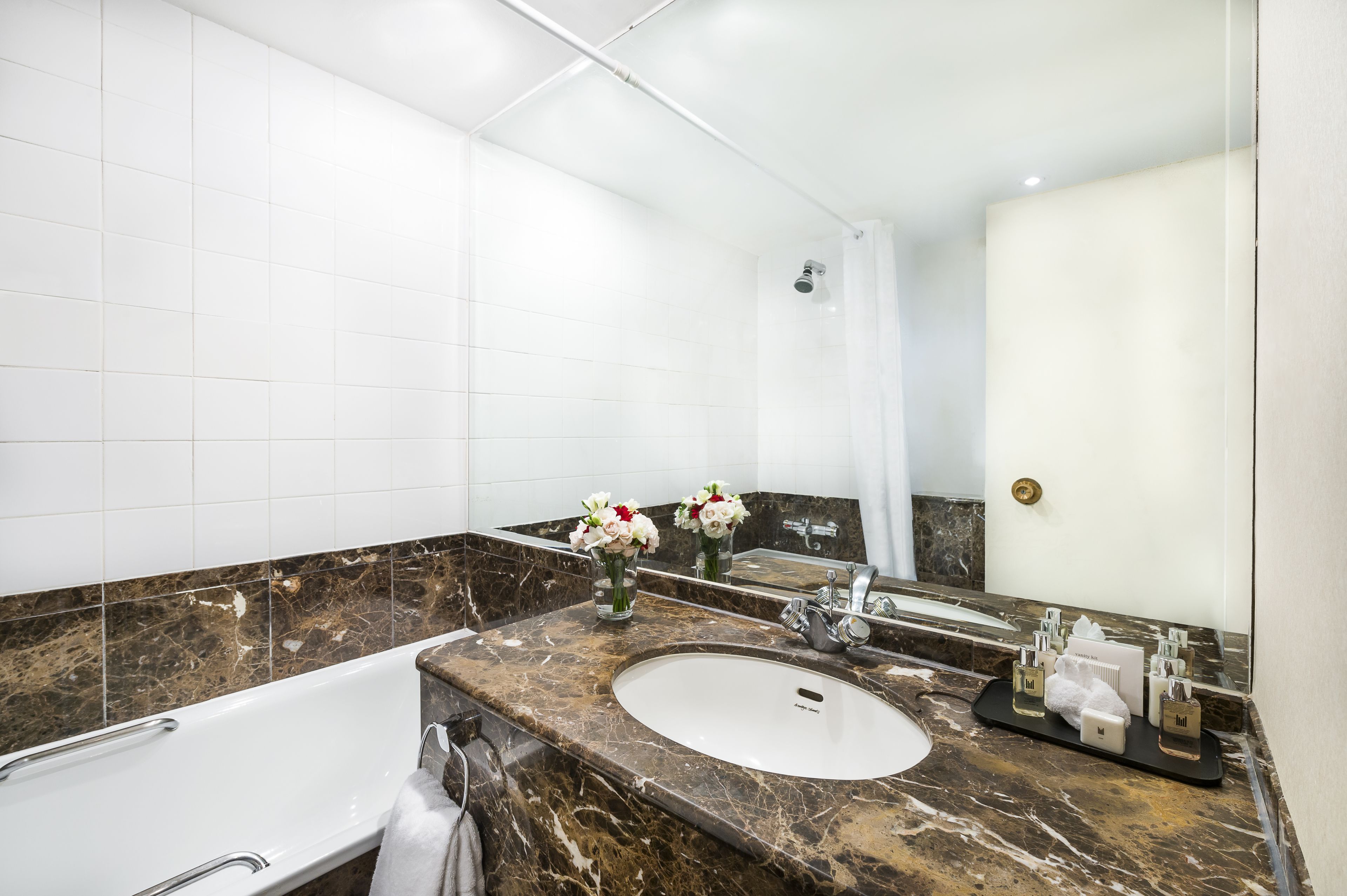 Un baño moderno con tocador de mármol, un espejo grande y una ducha.