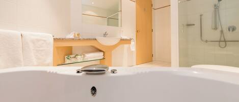 A modern bathroom with a large bathtub, a glass-enclosed shower, and a vanity with a mirror.