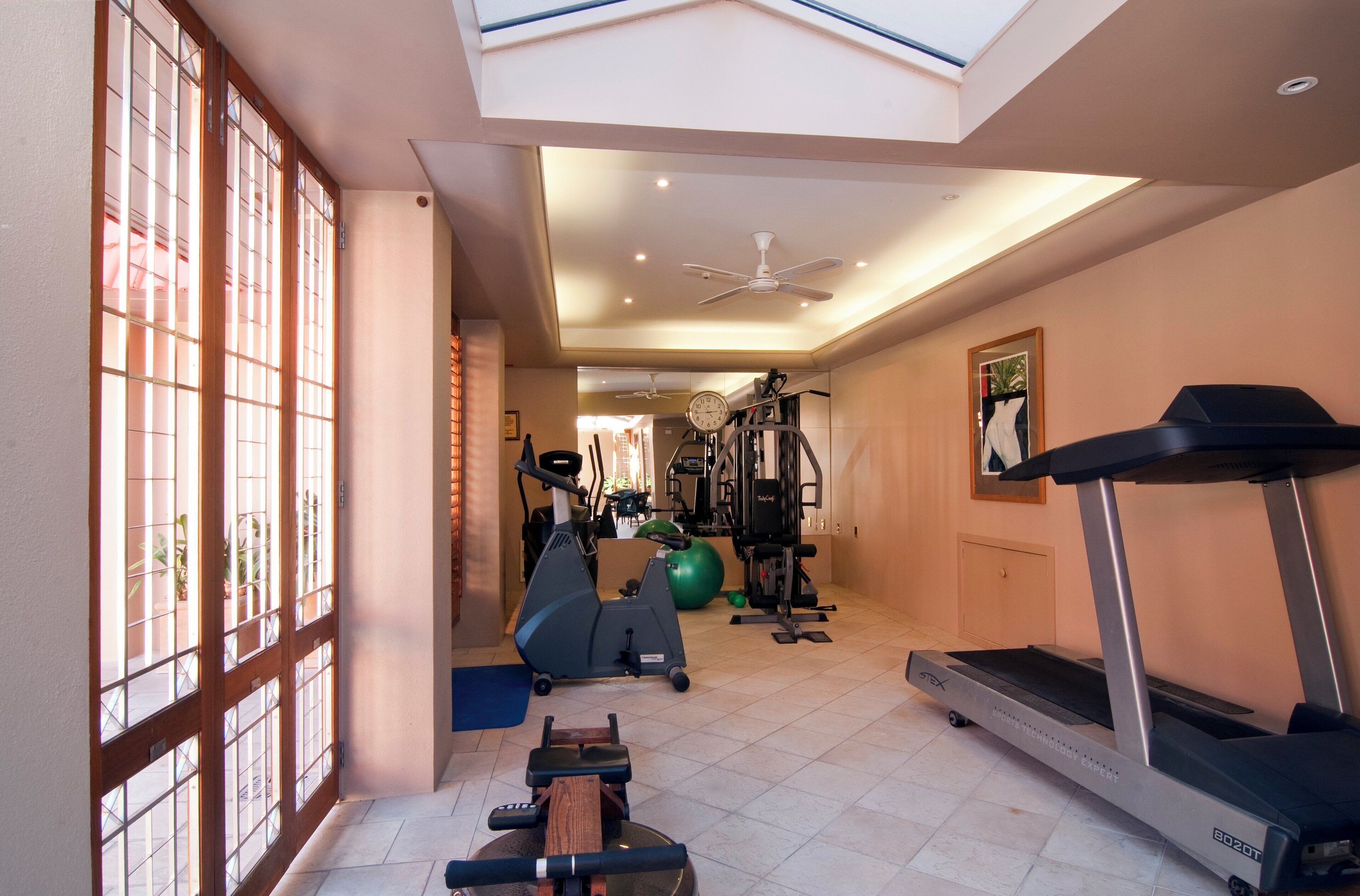 Een sportschool thuis met een loopband, elliptische trainer en fitnessballen.