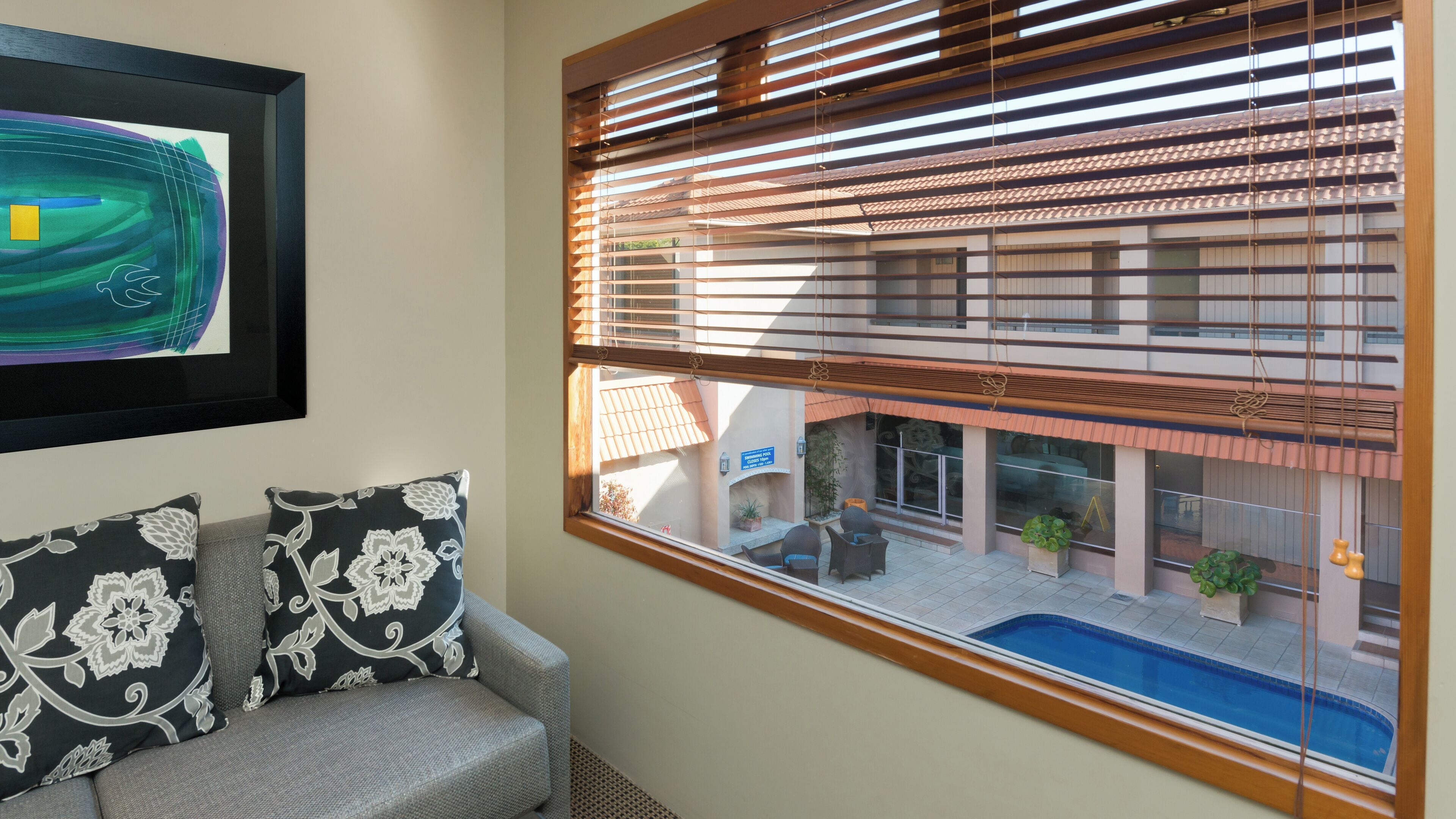 Una habitación con vista a una piscina y un edificio cercano.