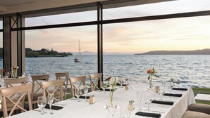 Mesa lista para comer con vista al agua y colinas al fondo.