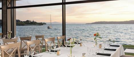 A table set for dining with a view of the water and hills in the background.