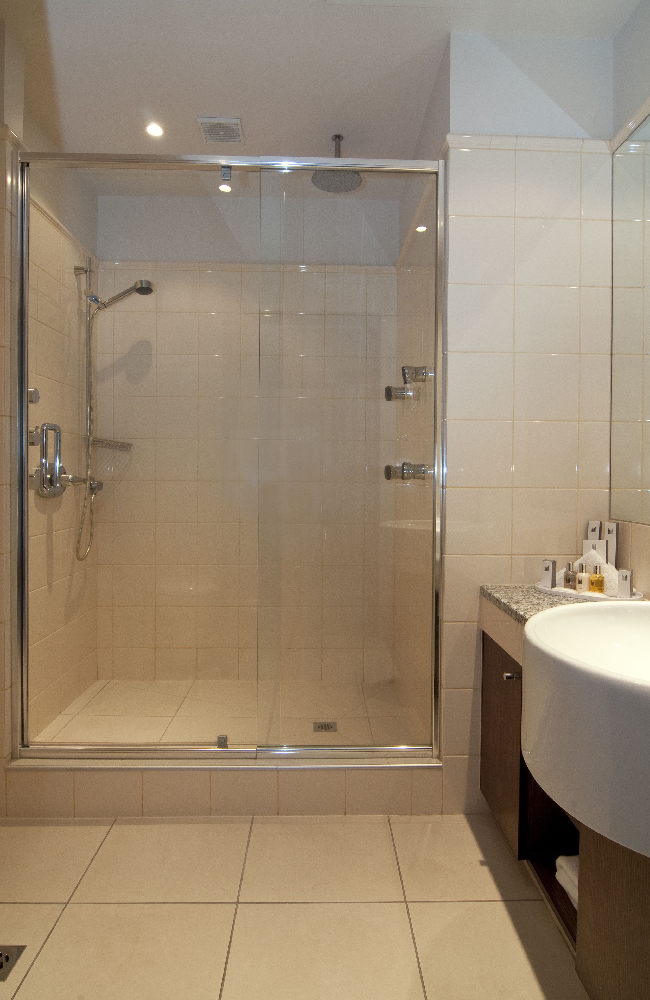 A modern bathroom with a glass-enclosed shower, a white sink, and tiled walls.