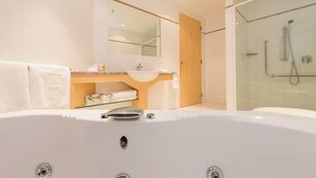 Un baño moderno con una bañera grande, una ducha con cerramiento de vidrio y un lavabo con espejo.