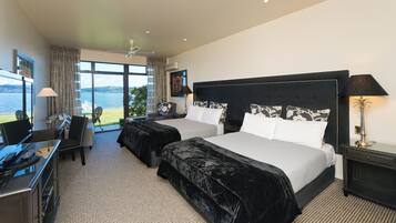 Habitación de hotel con dos camas, un escritorio y una silla. Amplia ventana con vista al mar.