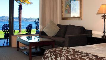 Habitación de hotel con sofá, una mesa, lámpara, una obra de arte enmarcada y vista al mar.