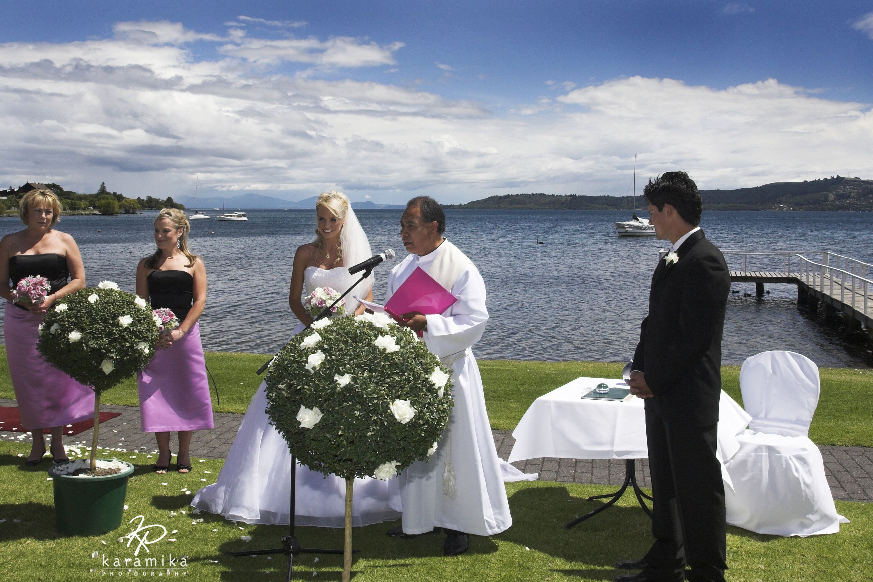 A wedding ceremony by a lake with a clear view of the water and distant hills.