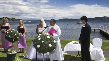 A wedding ceremony by a lake with a clear view of the water and distant hills.