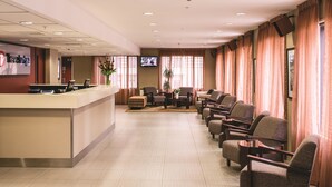 Un espace d’accueil d’hôtel comprenant un comptoir, des sièges et un téléviseur.