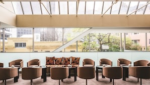 Une salle de réunion moderne dotée d’une grande fenêtre, d’un canapé et de plusieurs chaises disposées autour d’une table centrale.