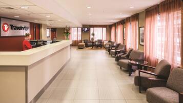 A Travelodge lobby with a reception desk, seating area, and a television screen.