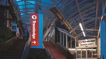 A Travelodge hotel entrance with a sign indicating Reception Level 7, a staircase, and a glass ceiling structure.