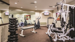 Une salle de sport équipée de divers appareils d’exercice, notamment des haltères, des tapis de course et des appareils de musculation.