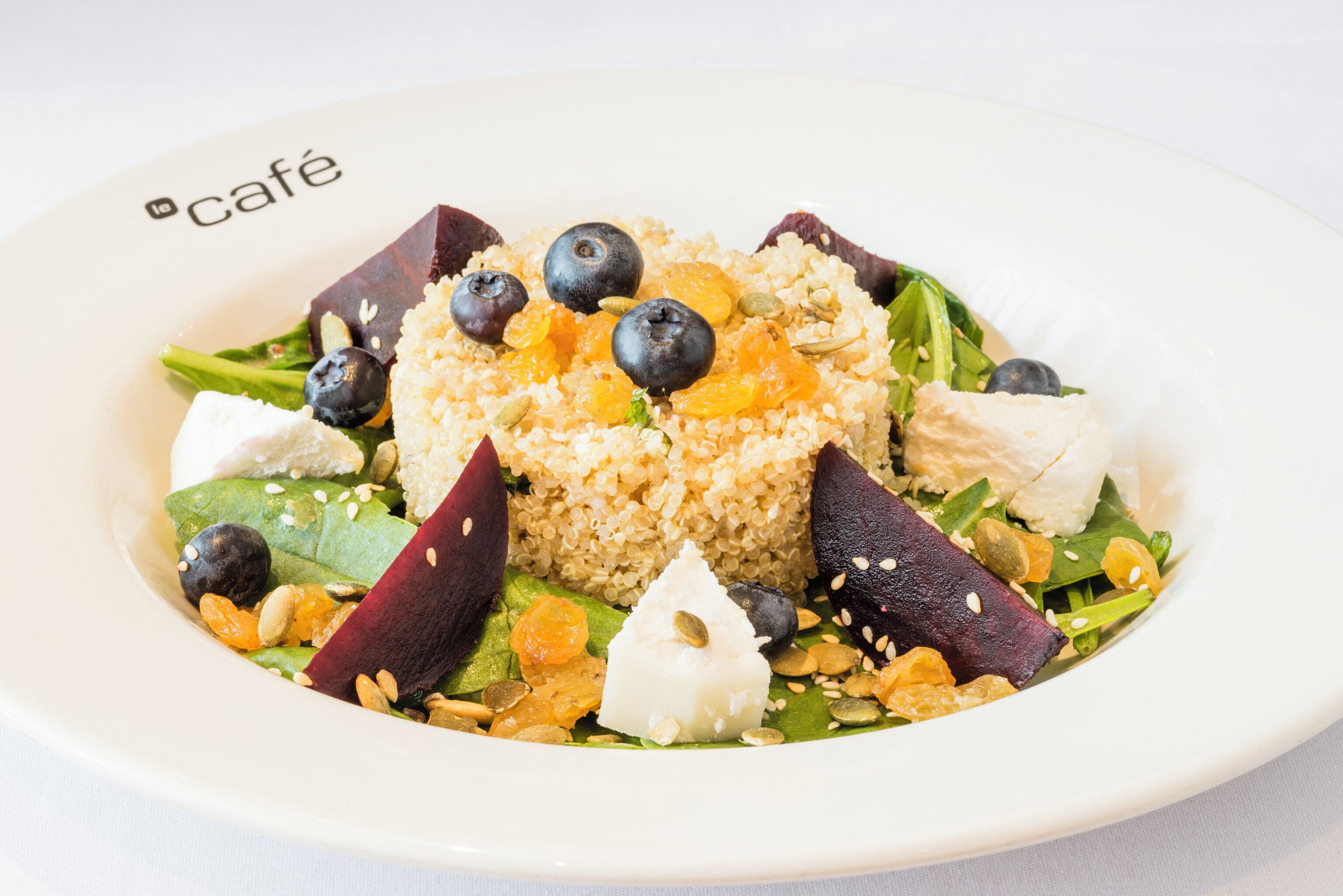 A plate of food with quinoa, fruits, nuts, and greens.