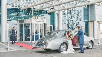 A wedding couple exiting a classic car from the entrance of the Anling Hotel.