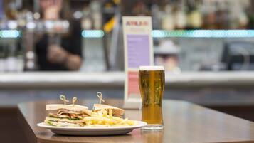 Un plato de comida y una jarra de cerveza sobre una mesa de madera en un bar.