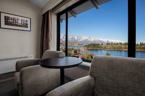 Ein Zimmer mit Blick auf Berge und einen See. Es gibt einen runden Tisch und zwei Stühle.