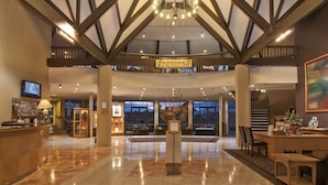 A spacious lobby with a high ceiling, a reception desk, a chandelier, and a sign reading "Impressions".