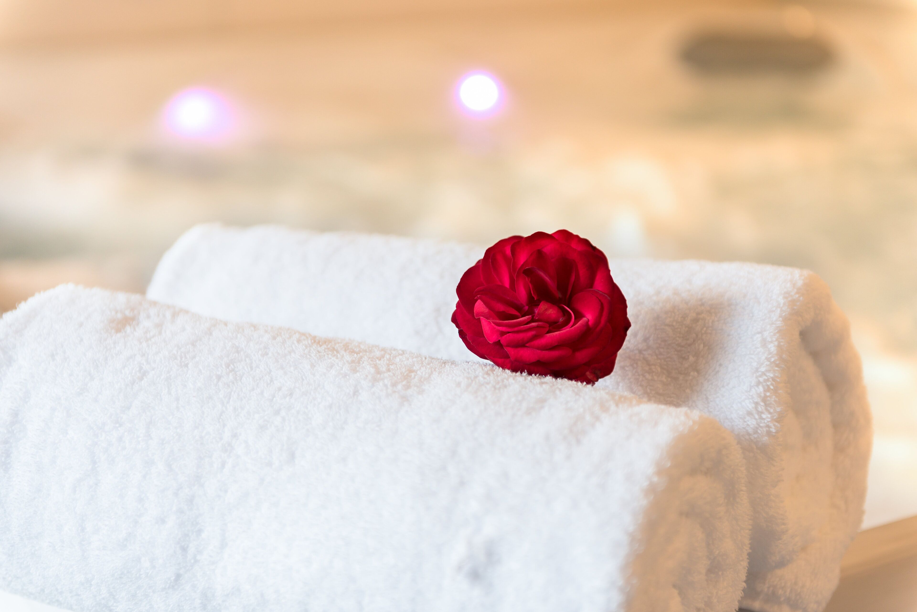 Duas toalhas brancas dobradas com uma rosa vermelha sobre elas.