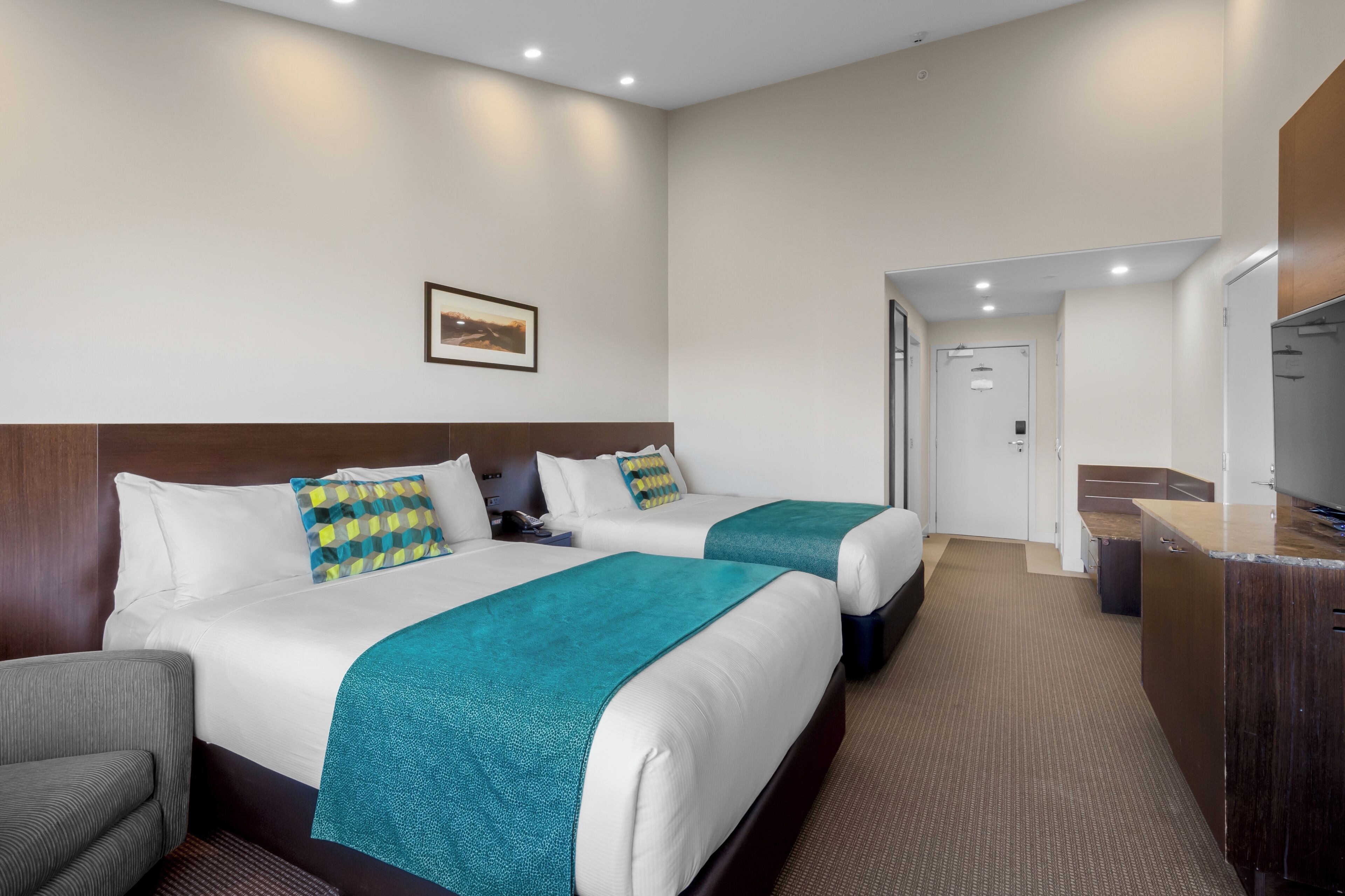 A hotel room with two beds, a desk, and a television.
