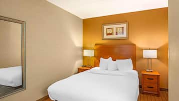 Una habitación de hotel con una cama grande, dos mesitas de noche, un espejo y un cuadro en la pared.