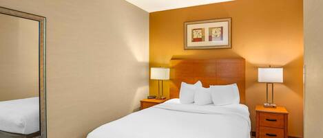 Una habitación de hotel con una cama grande, dos mesitas de noche, un espejo y un cuadro en la pared.