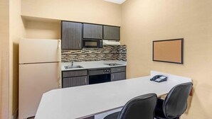 A compact kitchen with a refrigerator, microwave, and sink, and a small table with chairs. - Extended Stay America Suites Lancaster County (Mountville)
