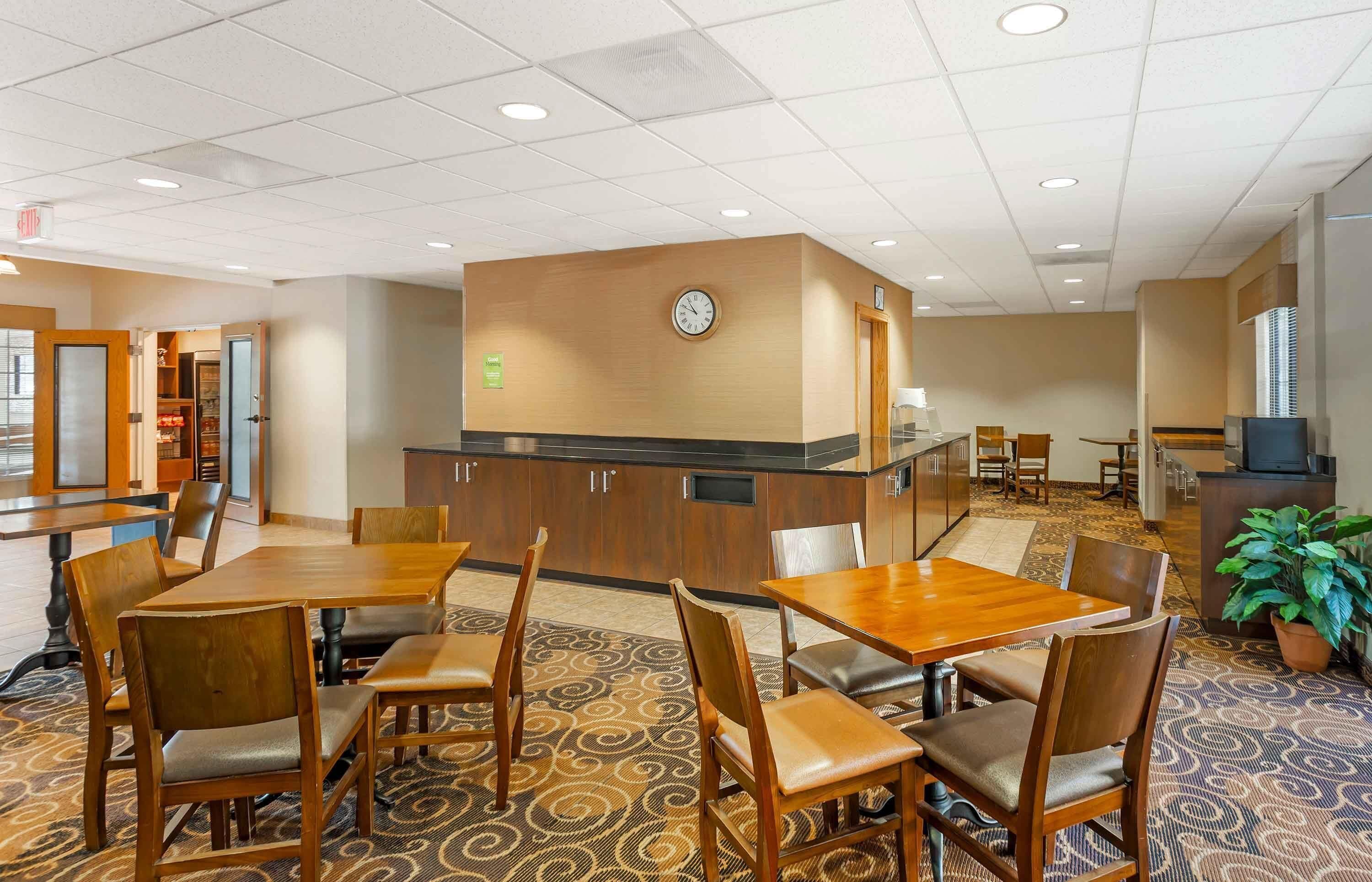 A hotel lobby with a reception desk, seating area, and a clock on the wall.