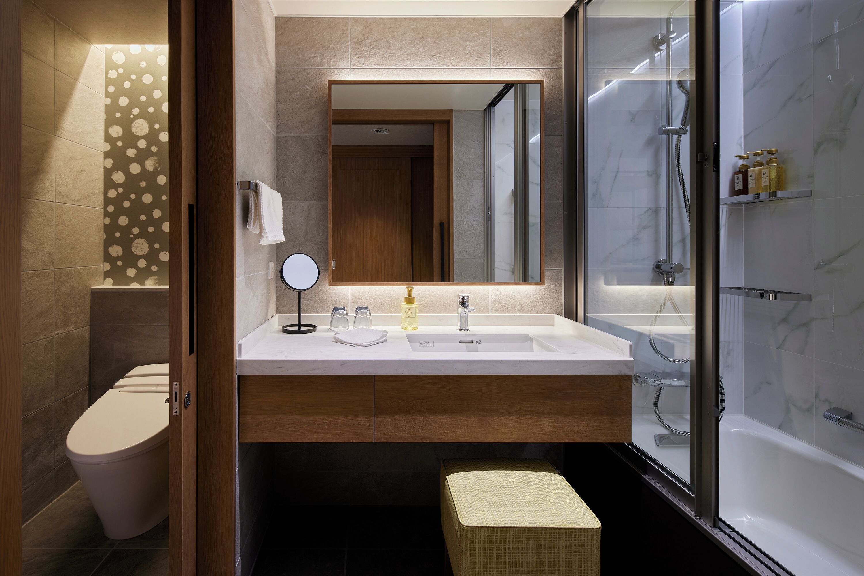 Un bagno moderno con servizi igienici, lavandino, specchio e doccia.