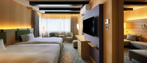 A hotel room with two beds, a desk, a TV, and a sofa.