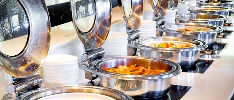 A buffet line with multiple stainless steel serving dishes, each with a lid.