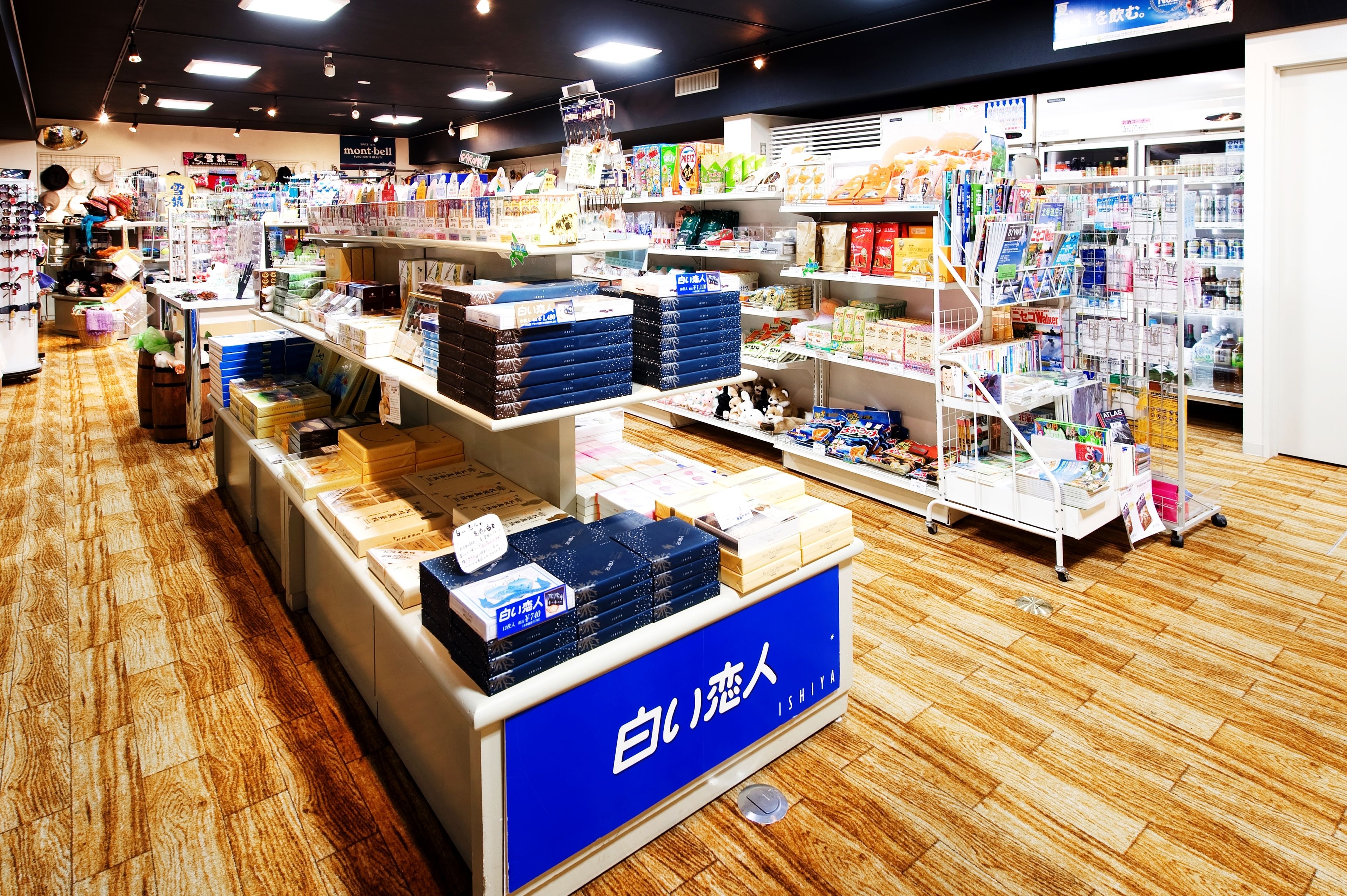 A bookstore with shelves stocked with books and magazines, a display counter with boxed items, and a sign in Japanese.